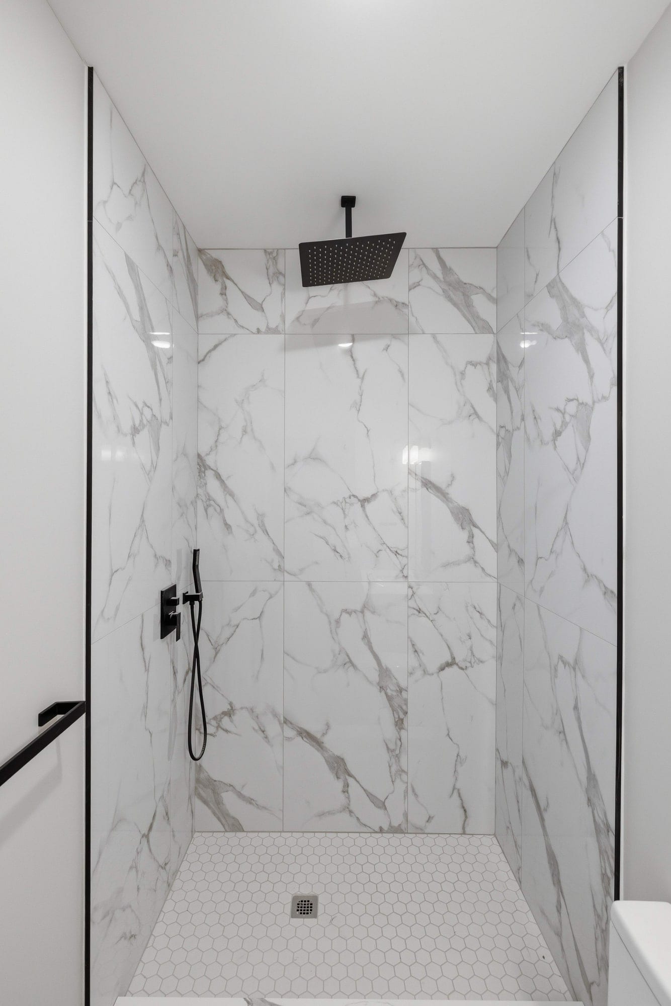 Walk-in shower tiled floor to ceiling, with a rainfall head and hex-tile floor